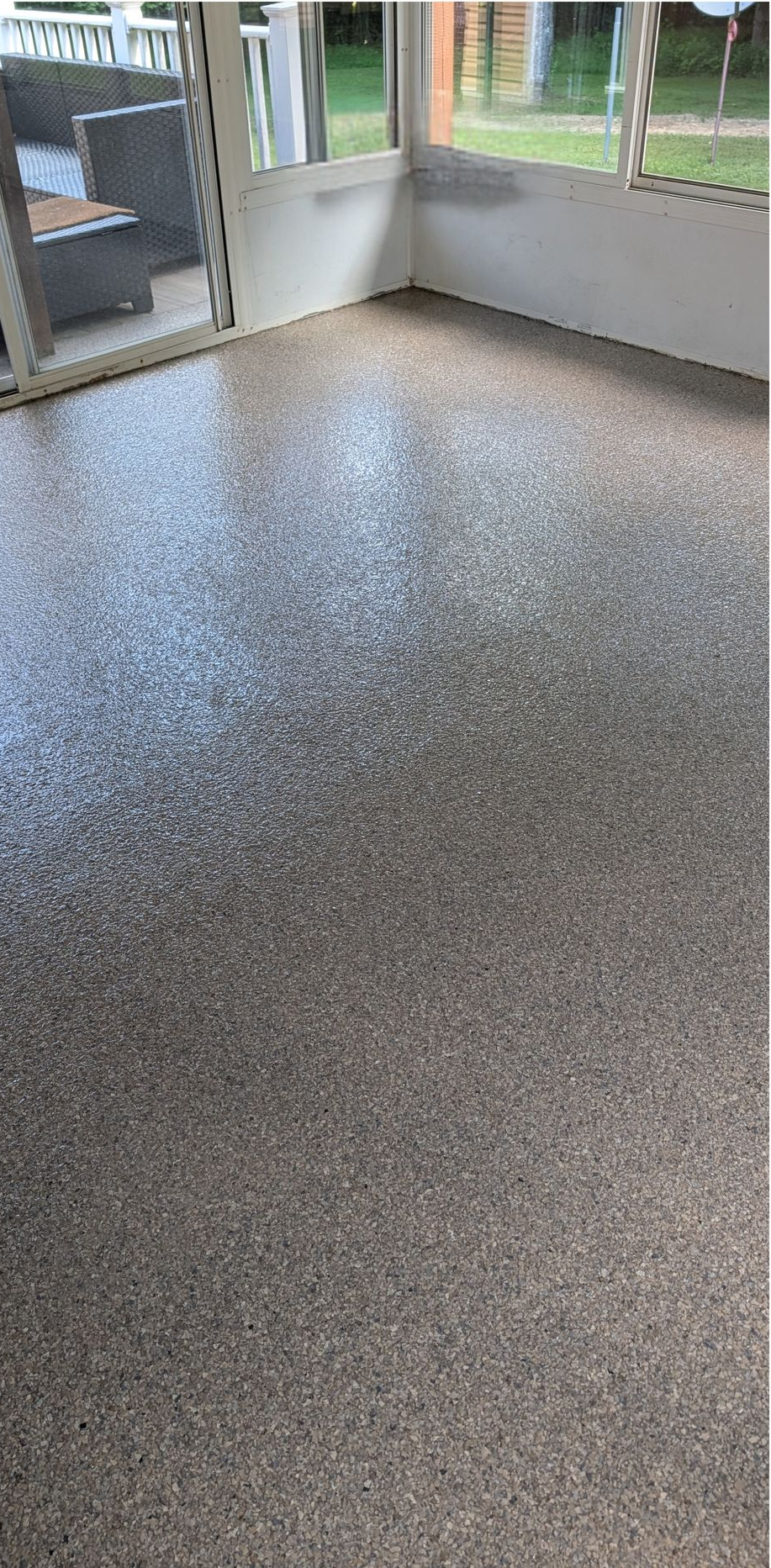 Empty basement with speckled epoxy floor and cinder block walls, lit by a bright floor spotlight.