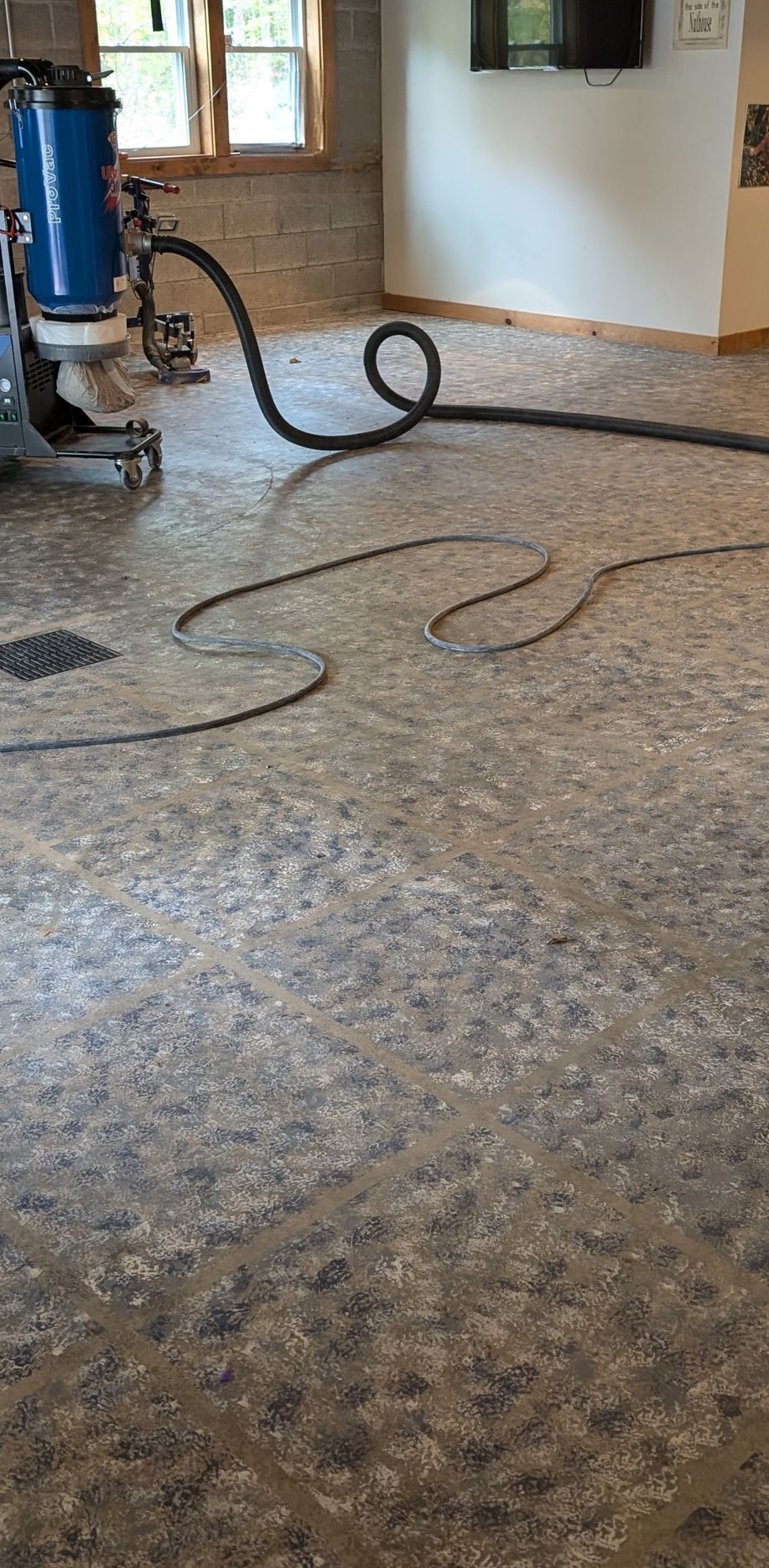 Vacuum cleaner and hose on a speckled floor in an empty room