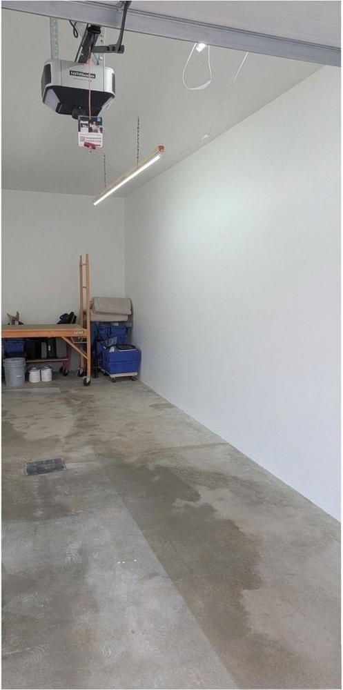 Empty basement with speckled epoxy floor and cinder block walls, lit by a bright floor spotlight.