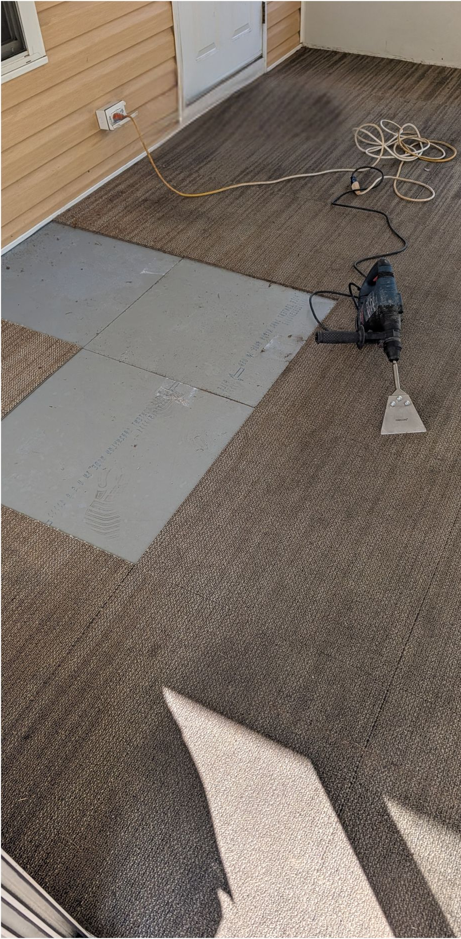 Empty concrete floor in a Lowe’s store with a small black display cart near the wall.