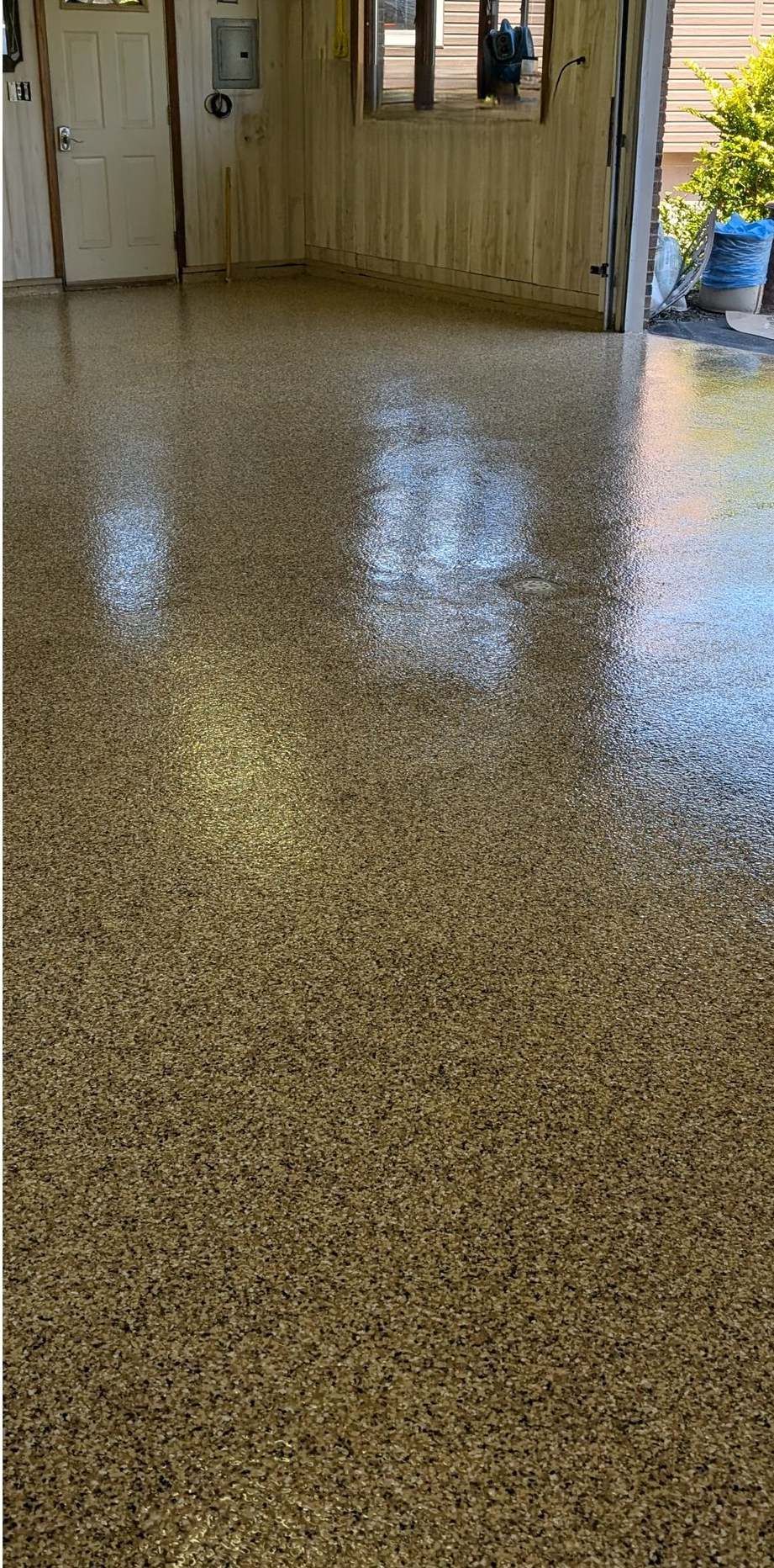 Shiny speckled epoxy floor in a bright room with open doors to a patio outside