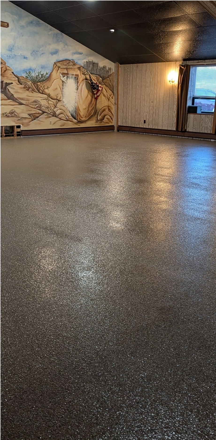 Empty indoor room with glossy speckled floor, mural wall, and windowed doorway.