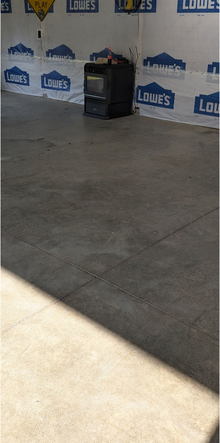 Empty concrete floor in a Lowe’s store with a small black display cart near the wall.