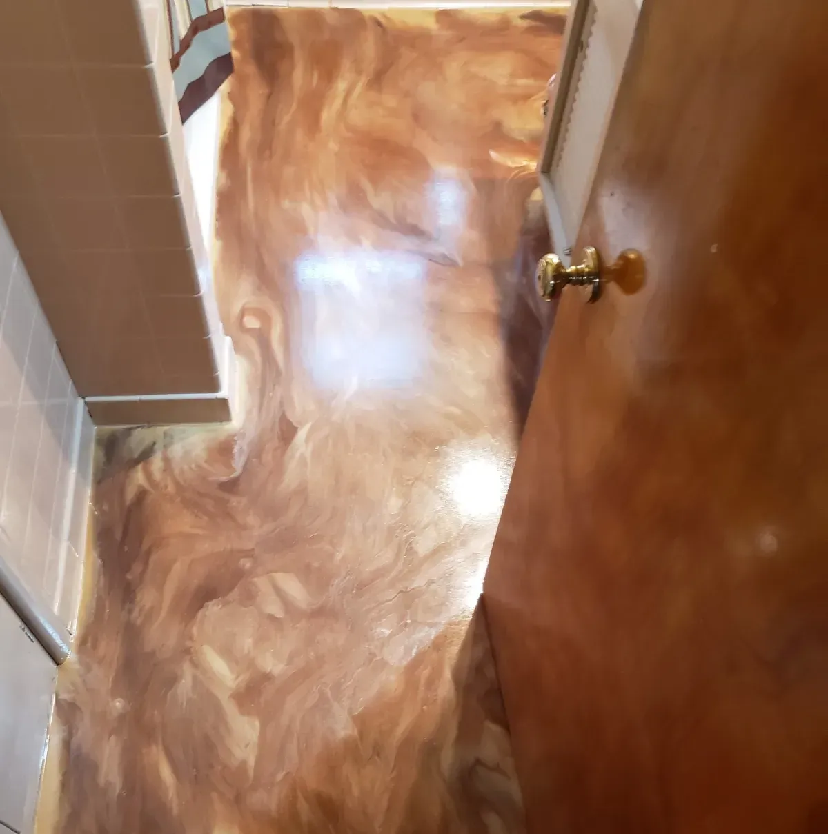 A hallway with a glossy wood floor and an open door with a brass knob on the right.