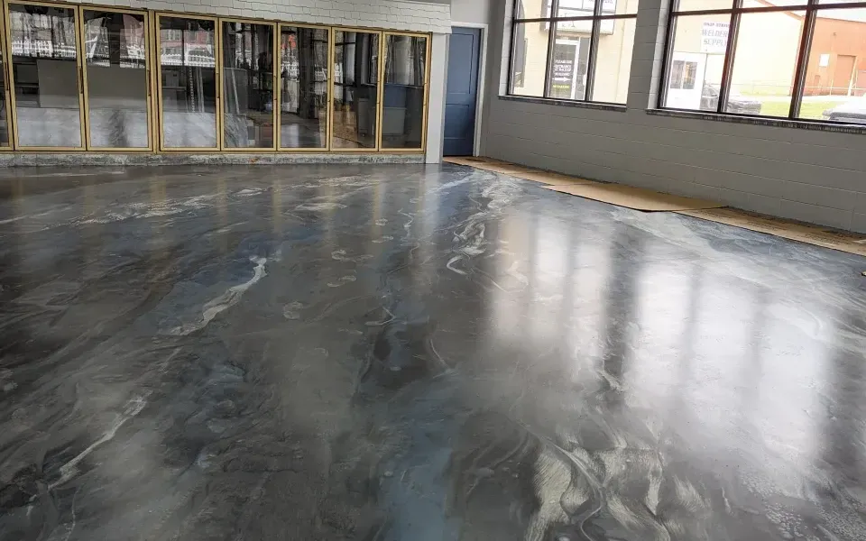 Empty room with a glossy dark floor and large windows along the walls