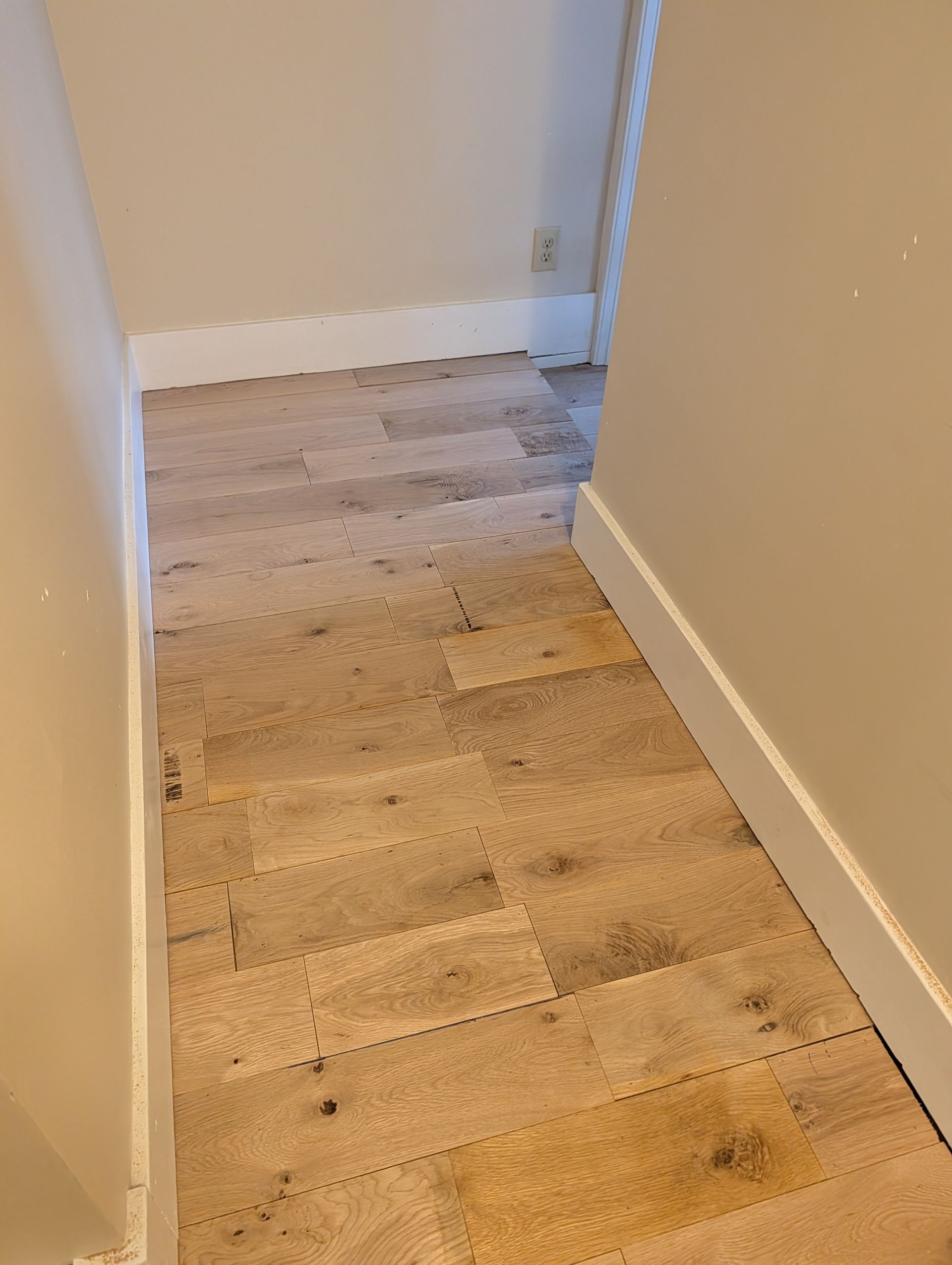Narrow beige-carpeted hallway with white walls and a stair lift track along the right side