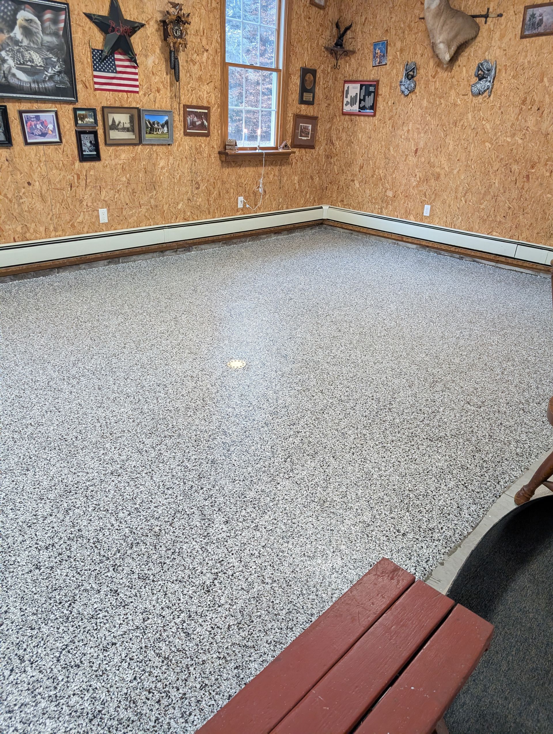 Speckled terrazzo floor in a small room with wood-paneled walls and framed photos.