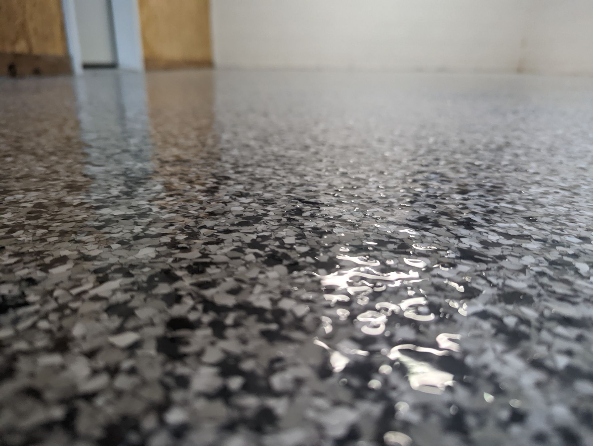 Close-up of a glossy speckled floor reflecting light in an indoor hallway