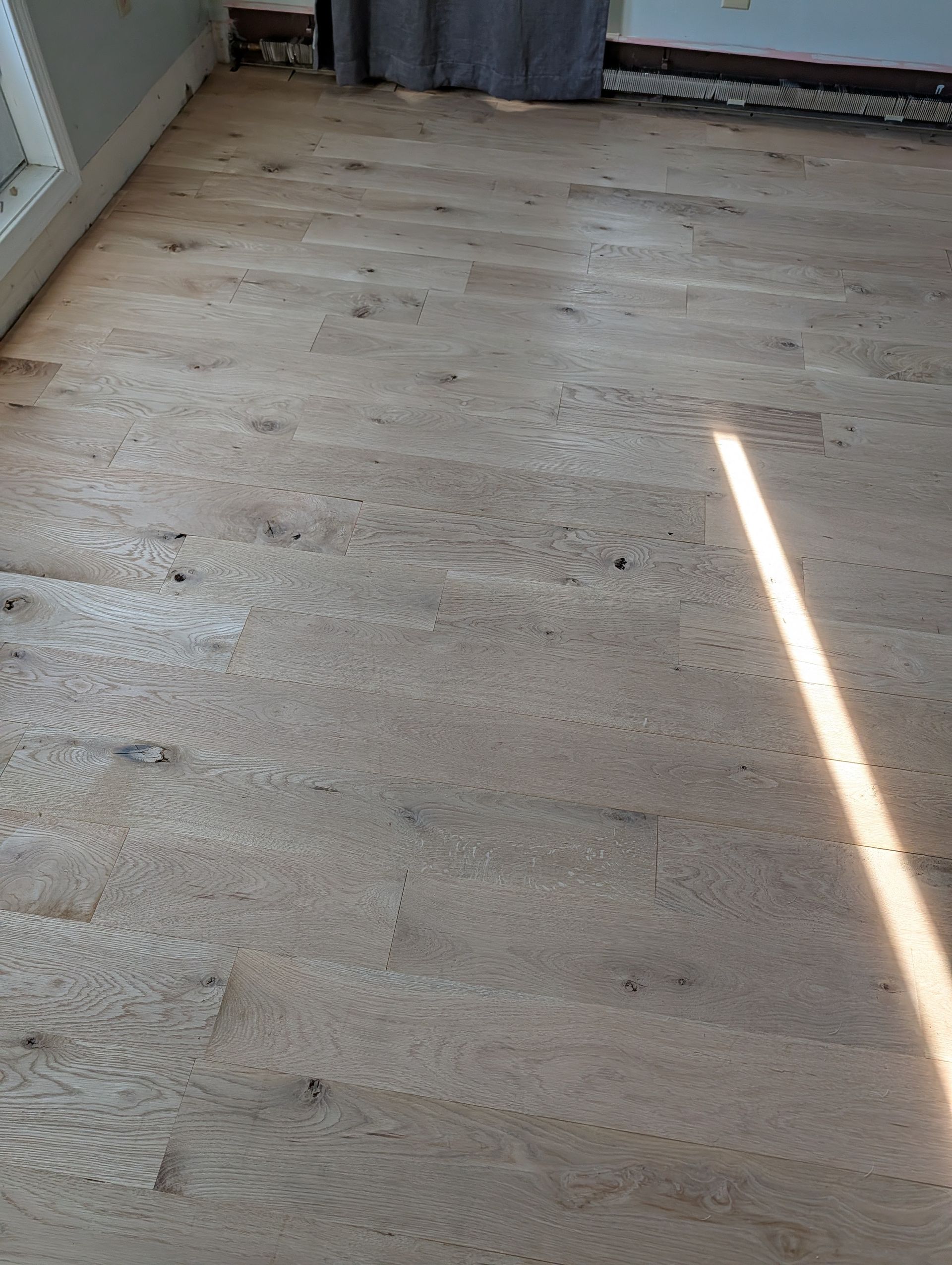 Bare bedroom floor with light wood planks and sunlight streaming across it