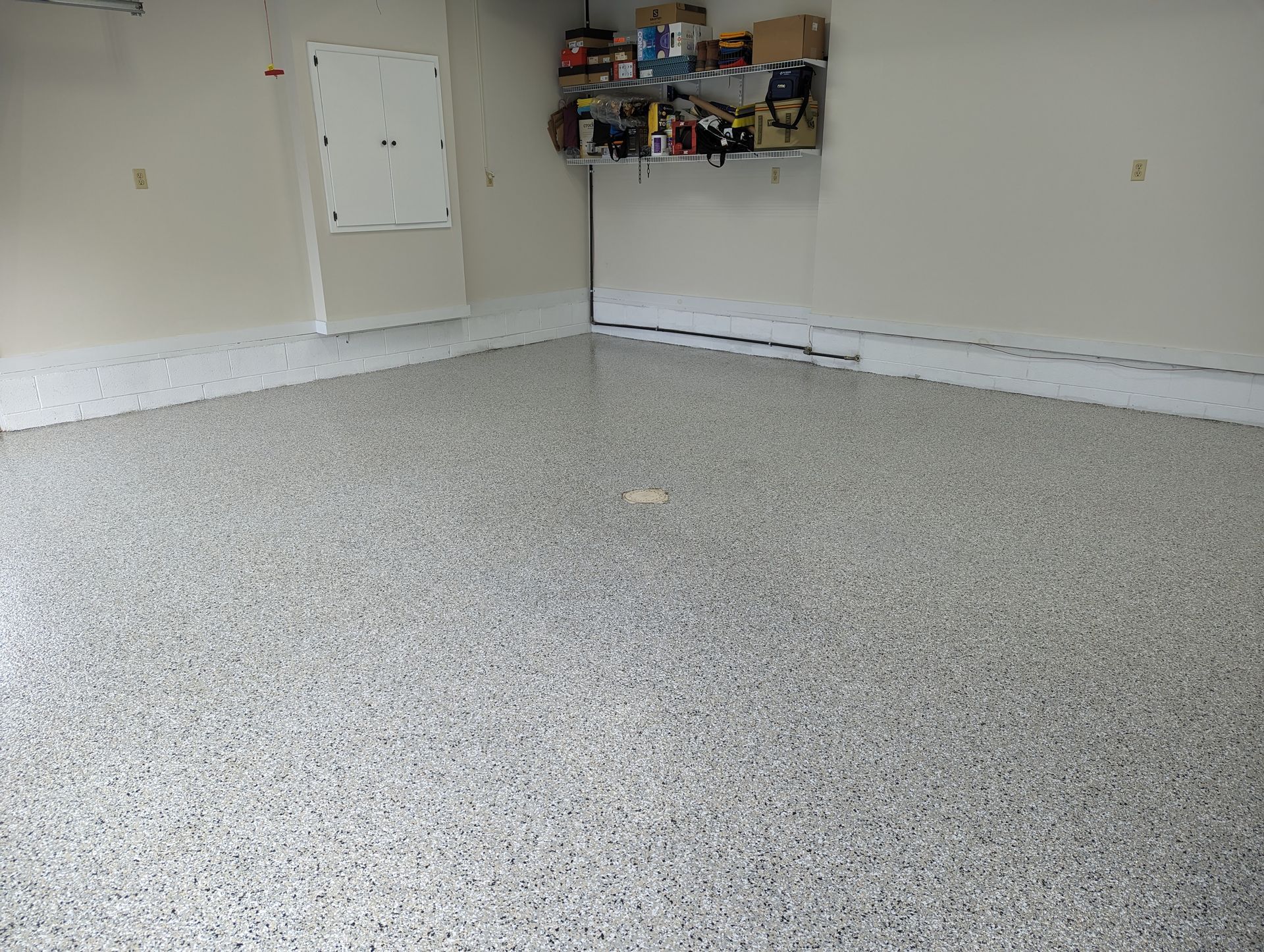 Empty garage with speckled epoxy floor and shelves on the back wall