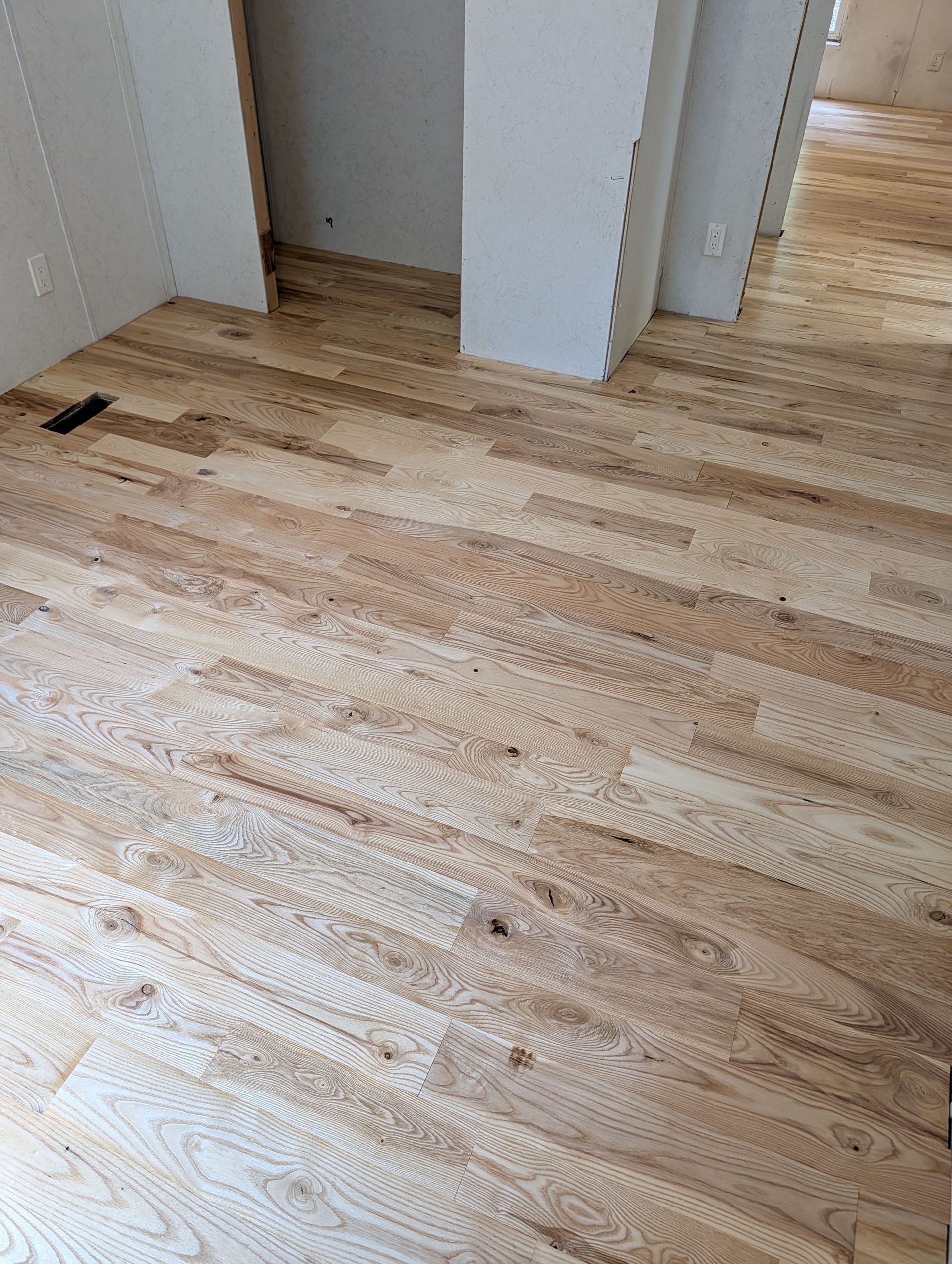 Empty room with light wood flooring and white walls, viewed from a doorway