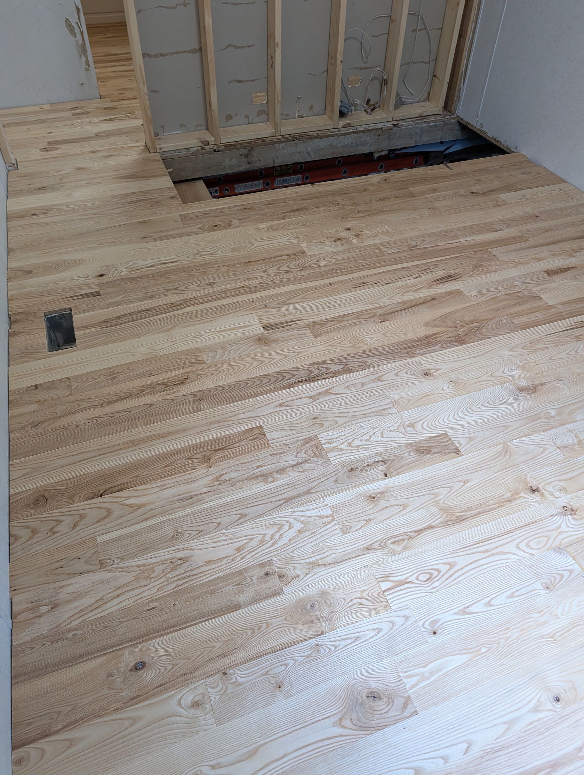 Bare wood floor under construction with an open doorway and unfinished wall framing