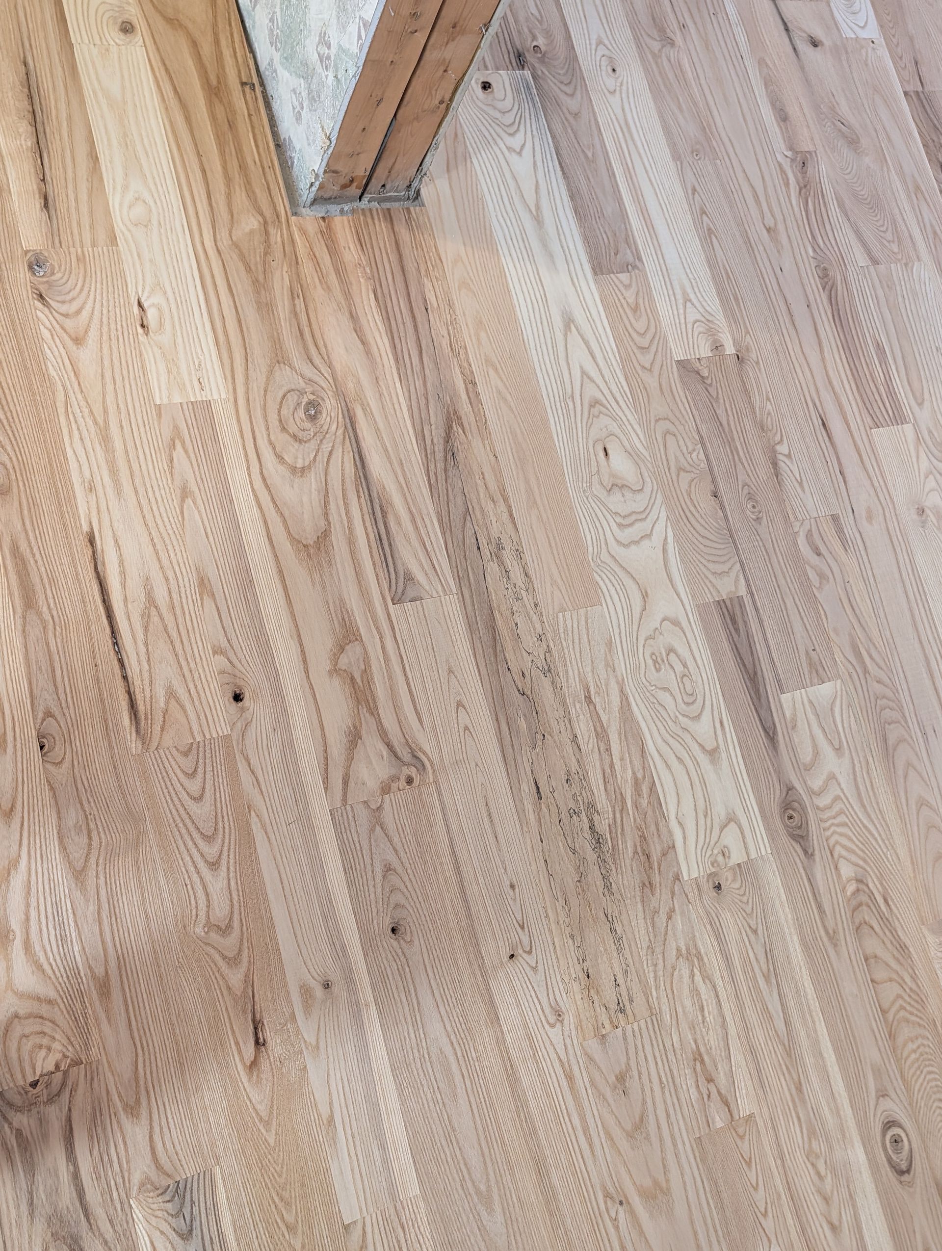 Light wood plank floor with a small metal furniture leg at the top edge