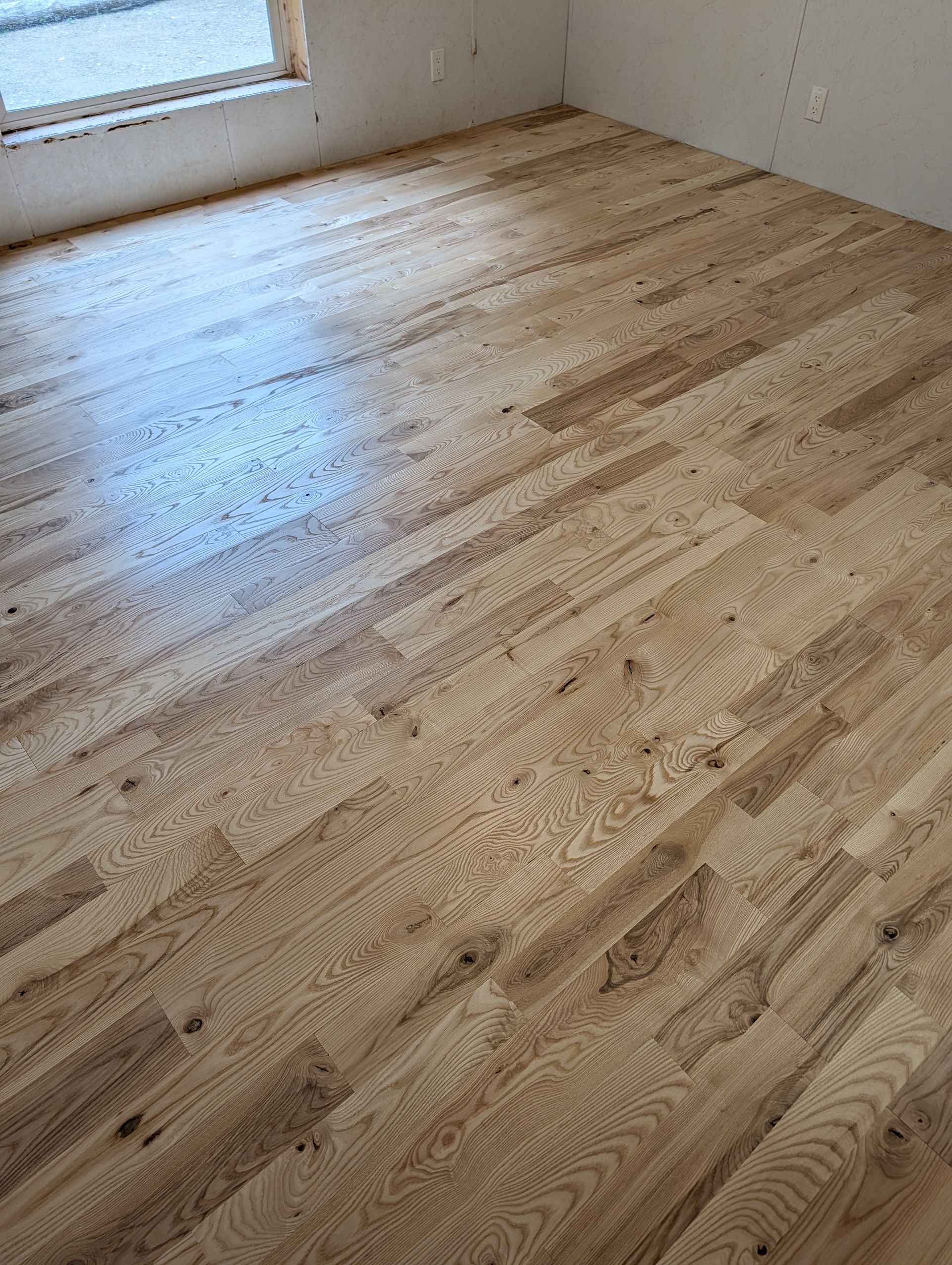 Sunlit hardwood floor in an empty room near a window