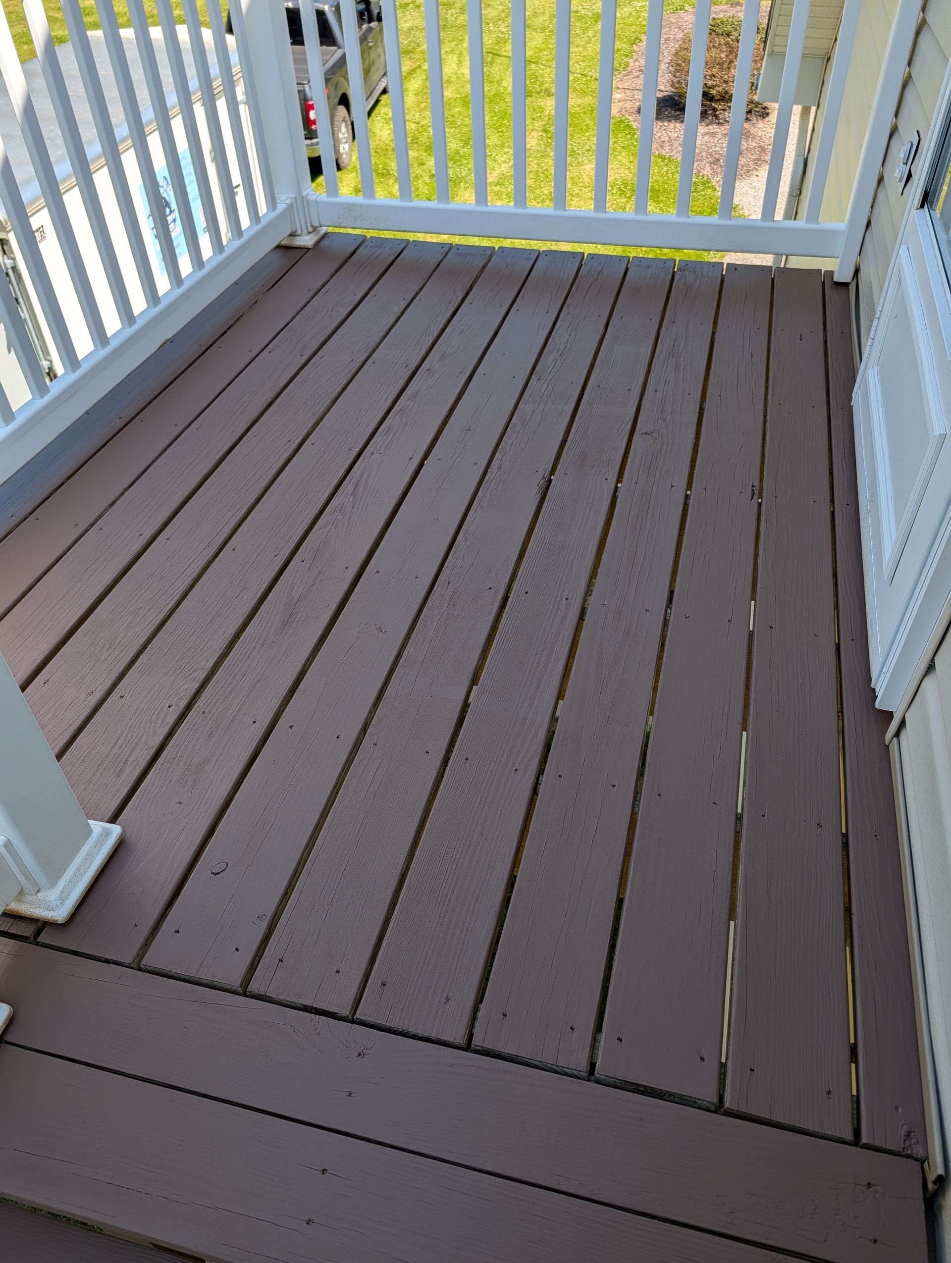 Brown composite deck with white railings and a view of green yard below