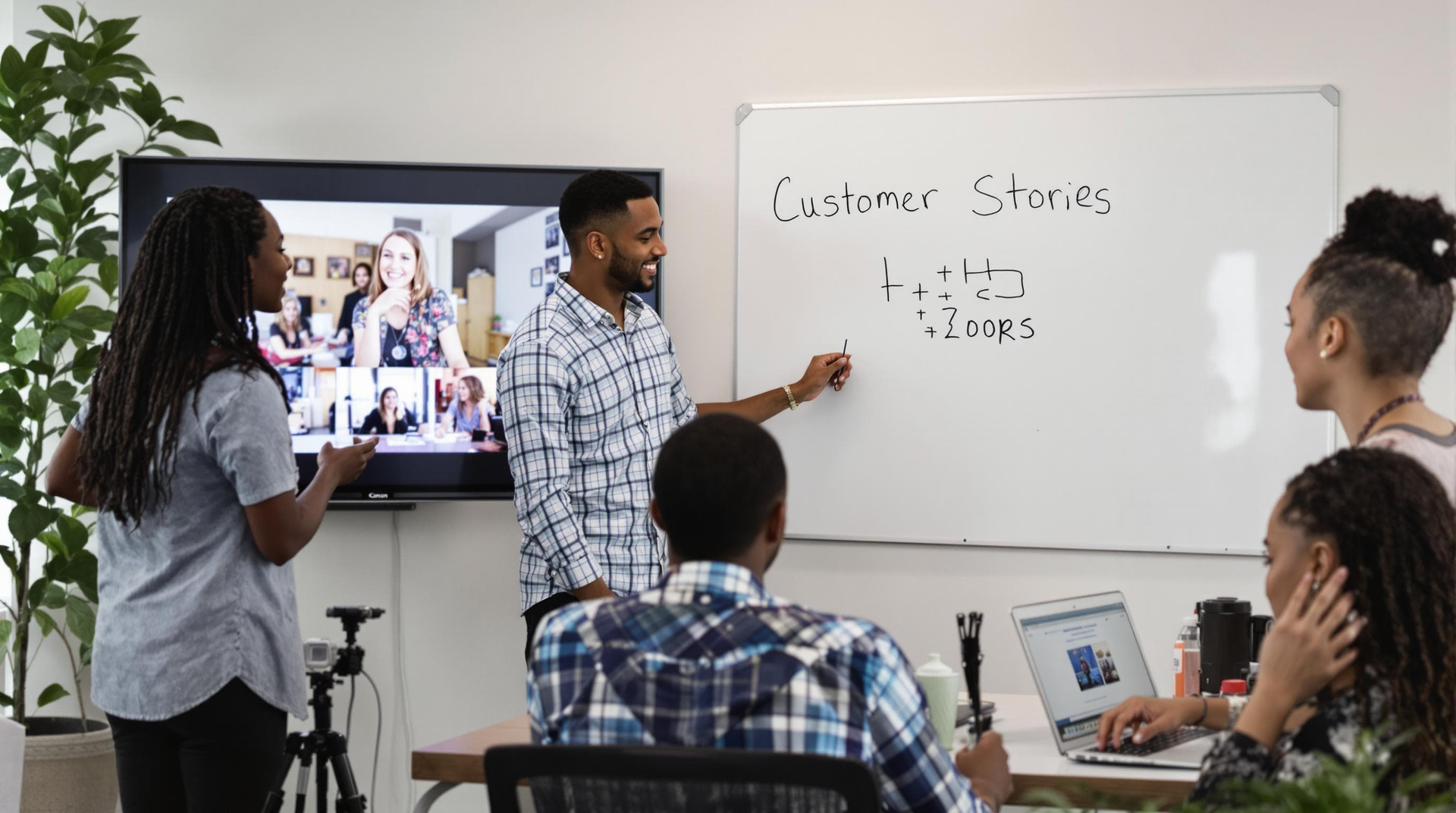 A group of people are sitting around a table in front of a whiteboard.