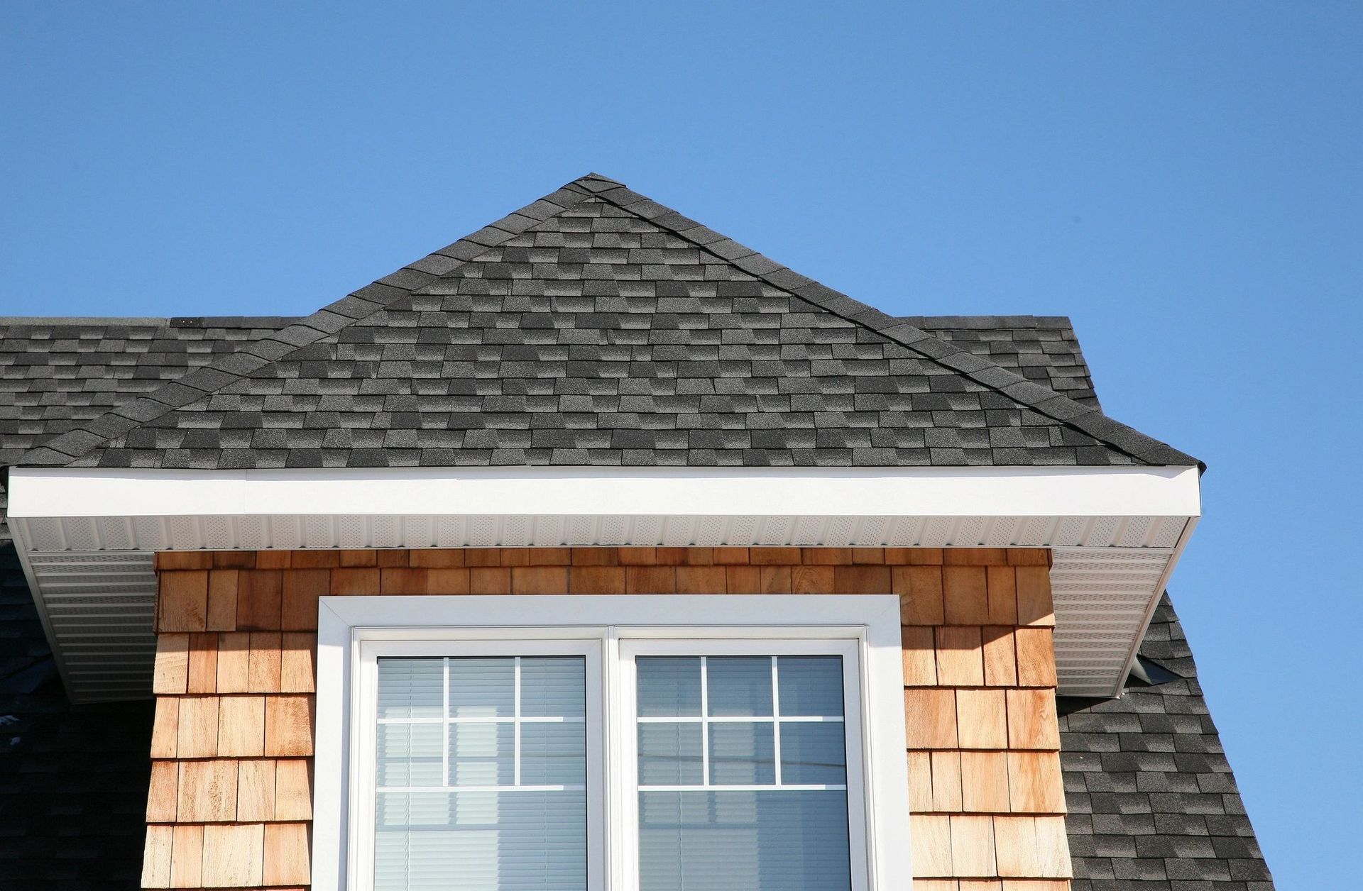 House roof and dormer window under a clear blue sky