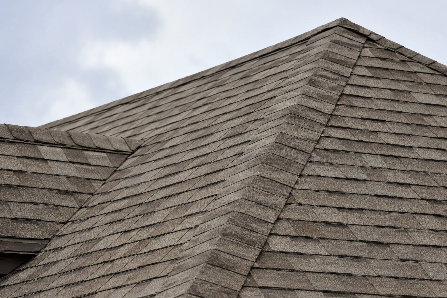 Gray shingled roof with a steep ridge and overcast sky