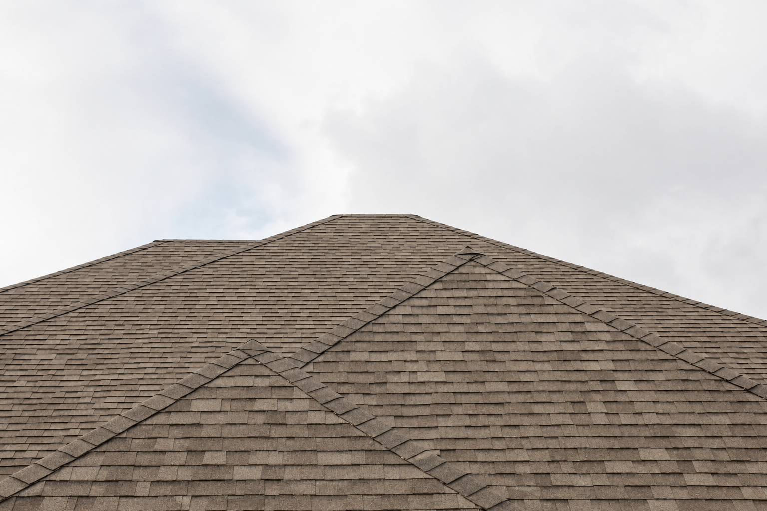 Dark gray shingled roof against a cloudy sky