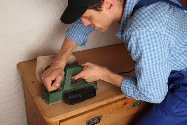 Woodworker using an electric hand planer on wood