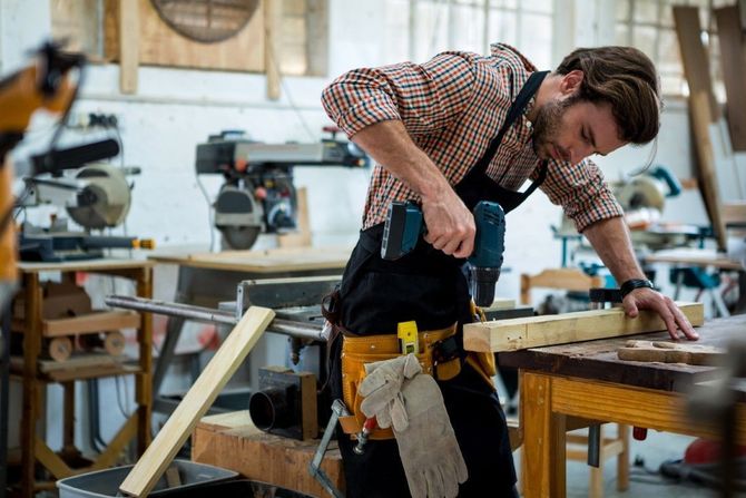 Woodworker using a power drill in a workshop