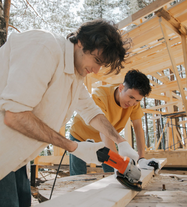 Two carpenters reviewing a wooden building frame.