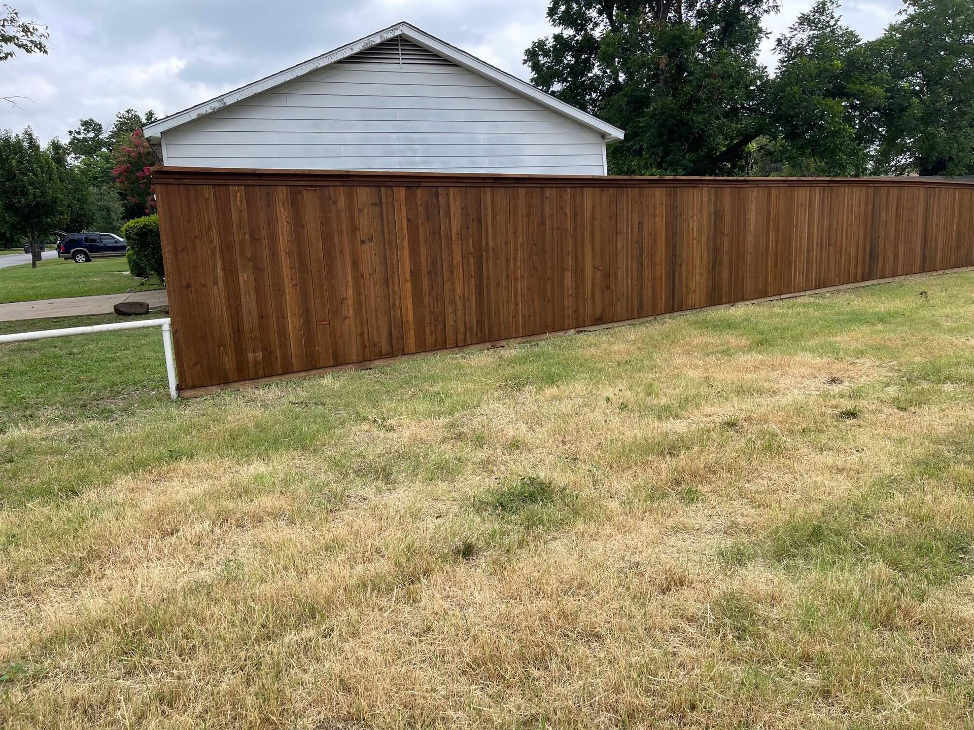 A Wooden Fence Surrounds a Grassy Yard in Front of A House