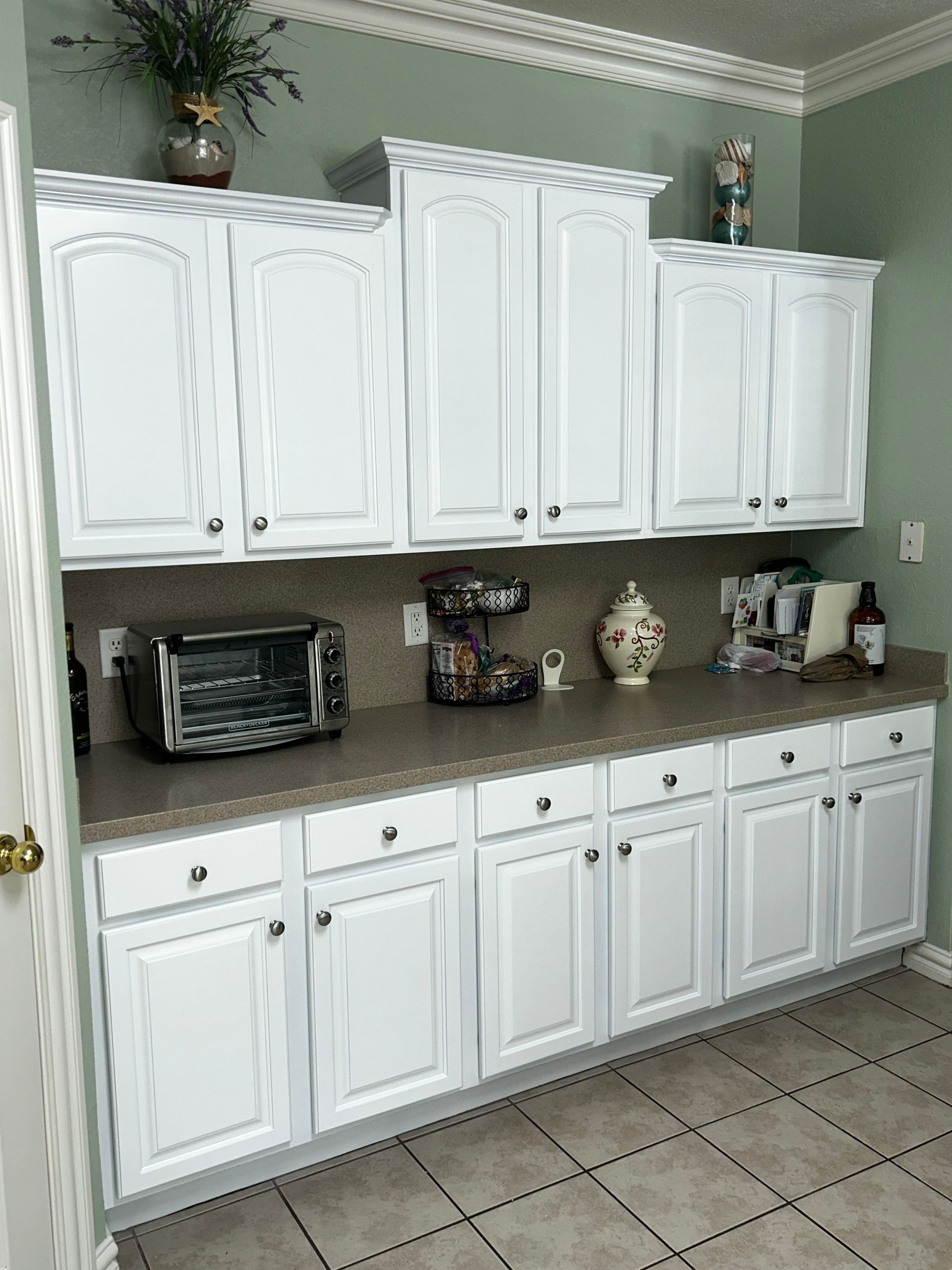 White kitchen cabinets with a countertop, a toaster, and decor.