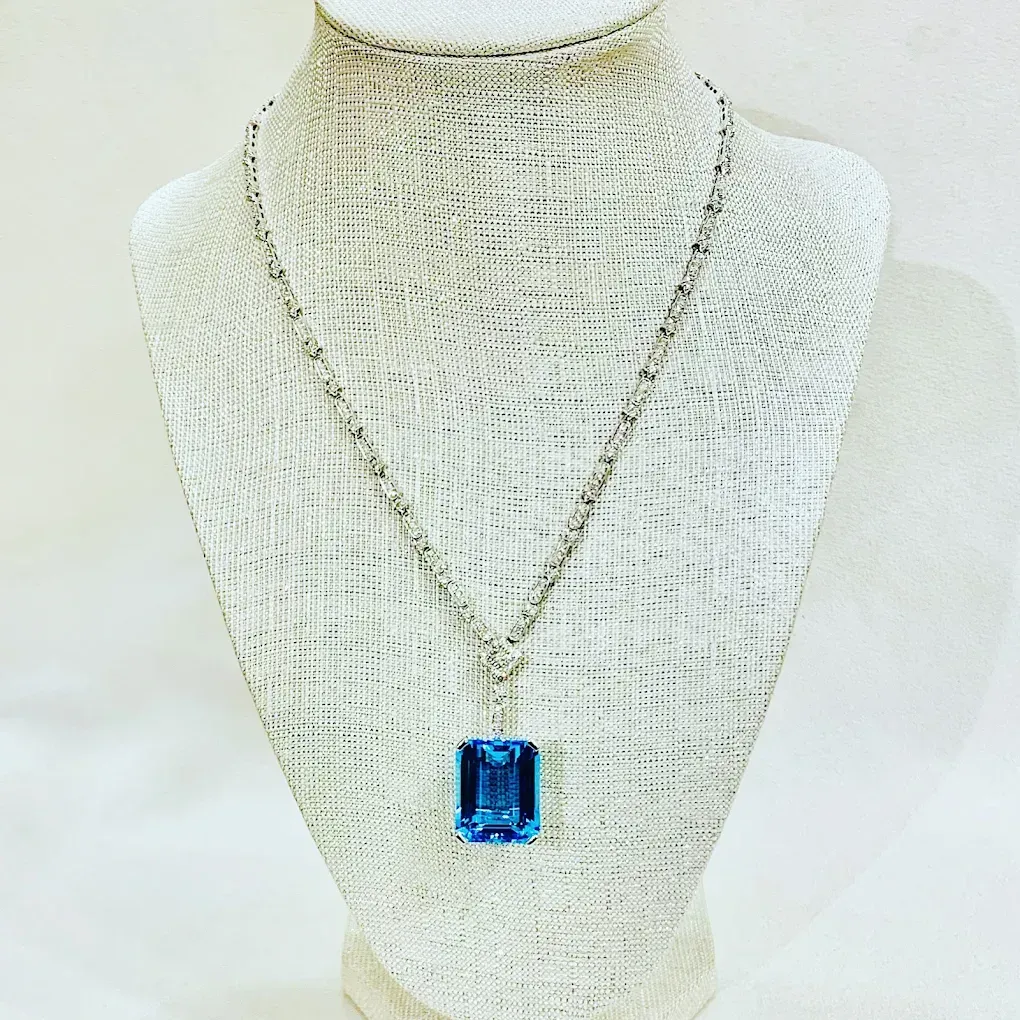 Blue rectangular pendant necklace on a cream knit display bust