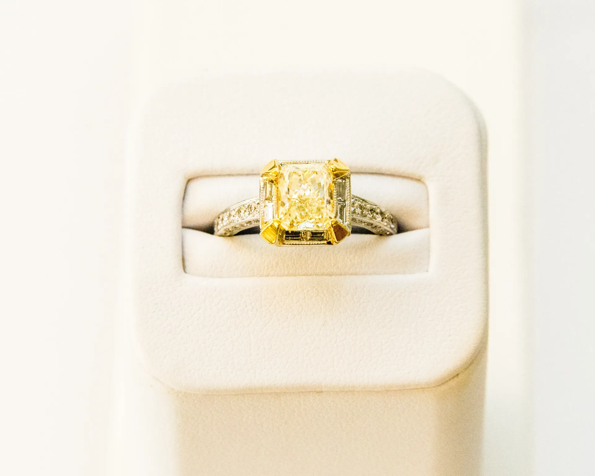 Yellow gemstone ring displayed in a white jewelry box with a padded insert