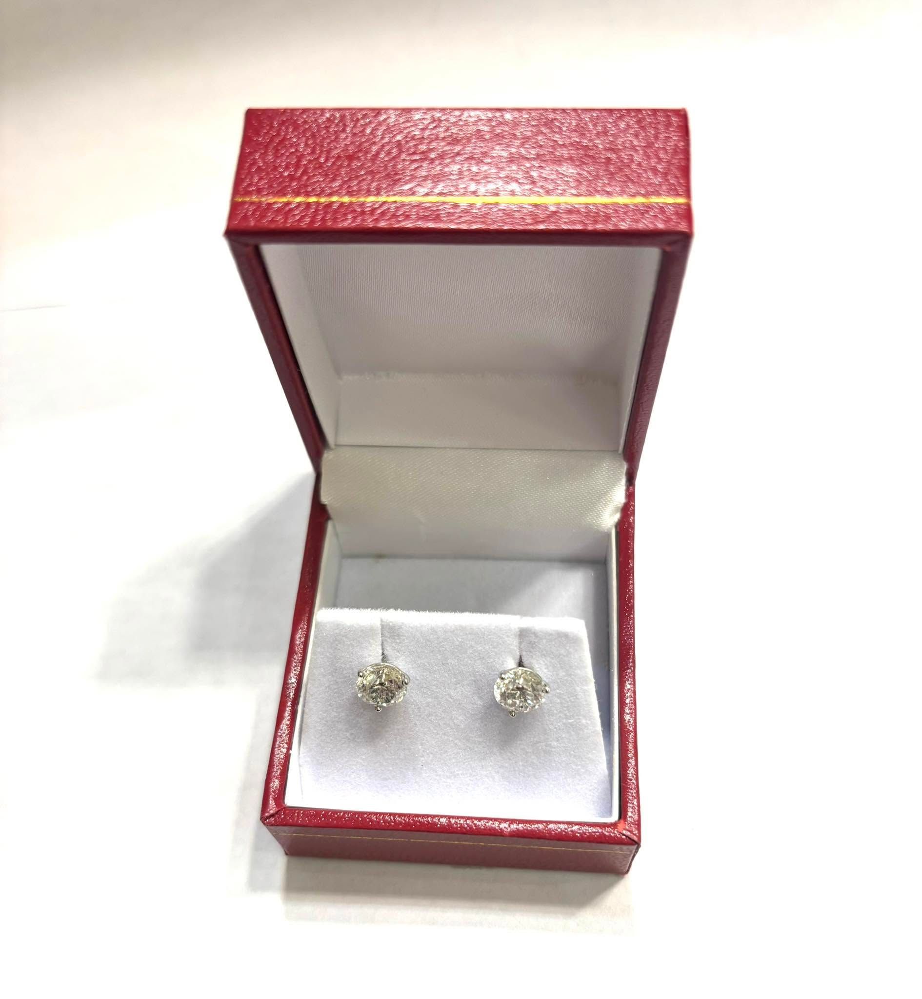 Red jewelry box with a pair of small stud earrings on white satin inside.
