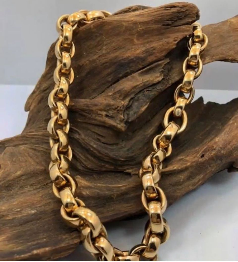 Gold chain necklace draped over a textured piece of driftwood