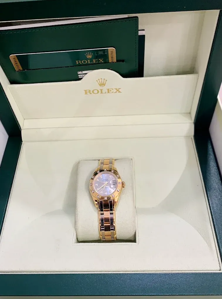 Rolex watch in an open presentation box, gold-toned with a white dial