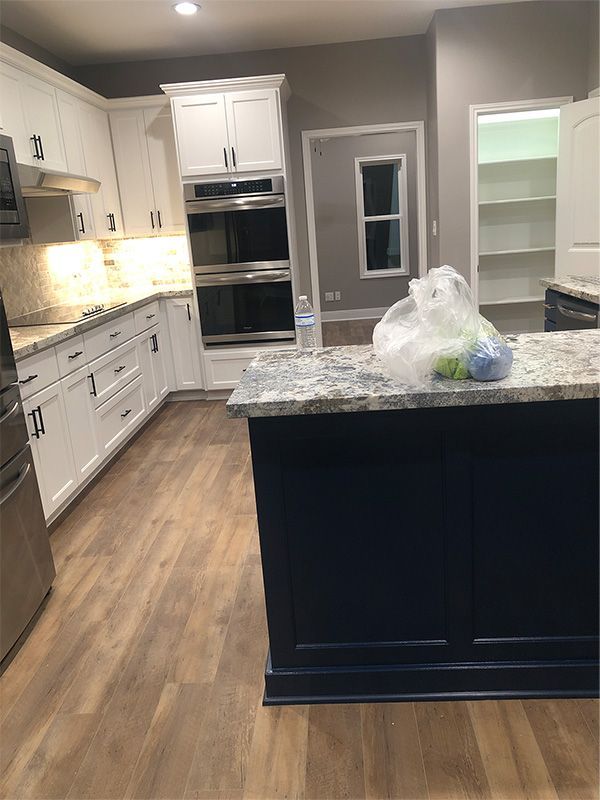 Kitchen with white cabinets, blue island, granite countertops, and stainless steel appliances.