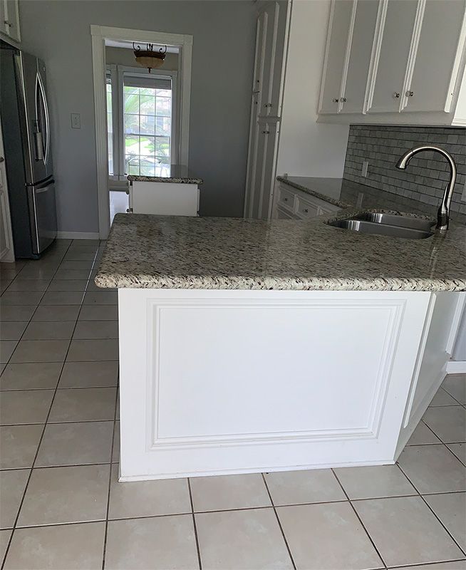 Kitchen with white cabinets, granite countertops, and a stainless steel refrigerator.