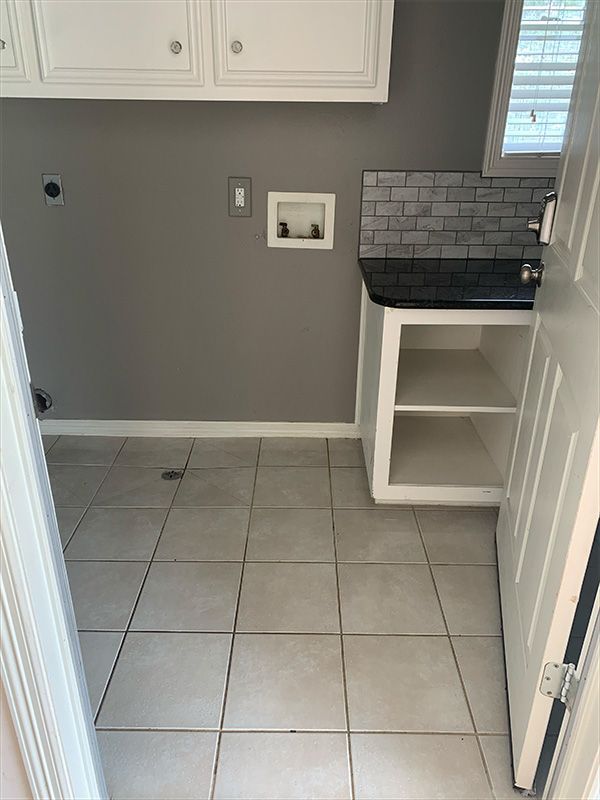 Laundry room with gray walls, white cabinets, and tiled floor.