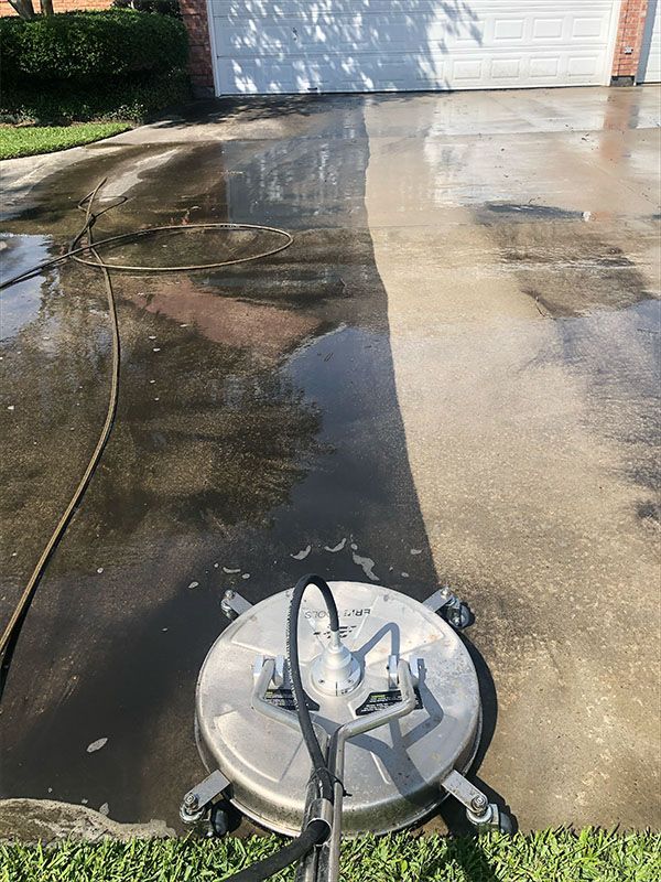 Pressure washer cleaning a driveway, showing a clear contrast between clean and dirty sections.