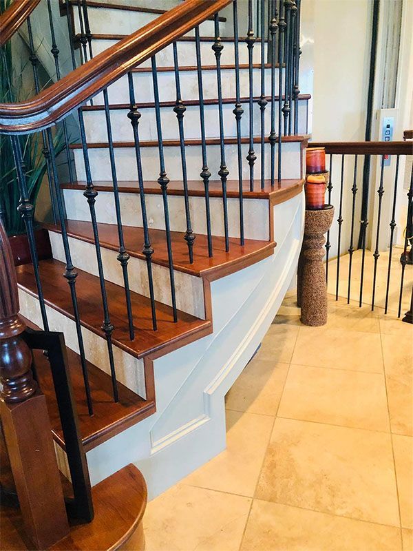 Wooden staircase with black iron balusters and brown handrails; cream-colored risers.
