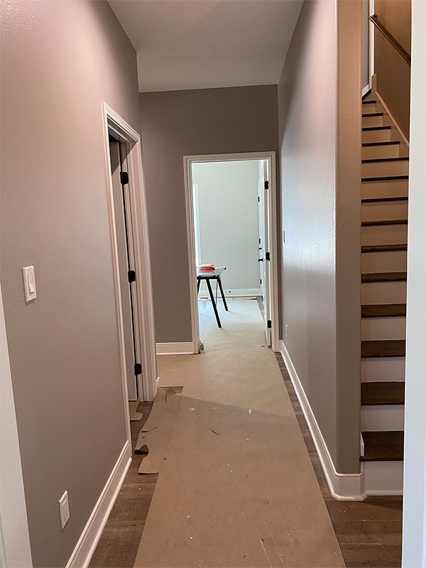 Hallway with gray walls, white trim, and a staircase on the right side. One door is open in the center.