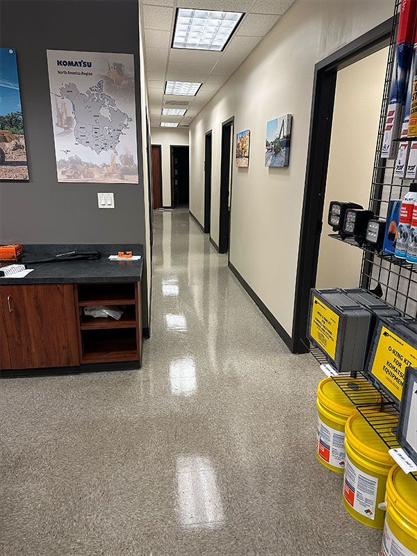 Hallway with doors, maps, and displays. Yellow paint buckets and black framed doors line the polished floor.