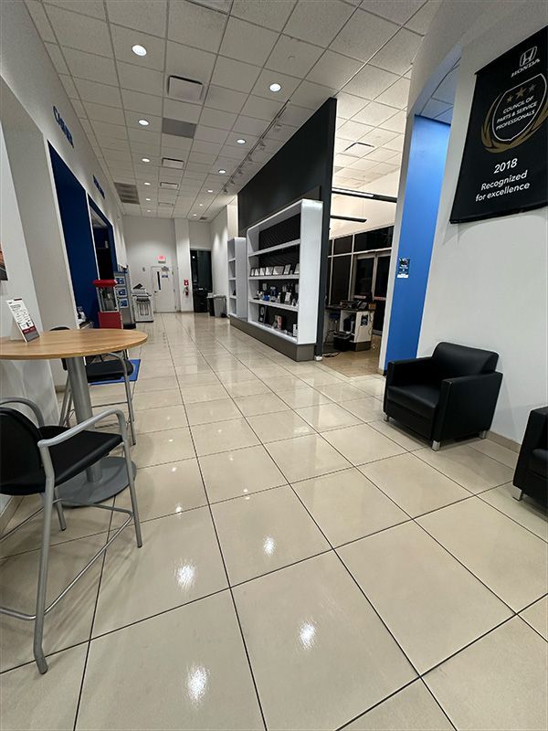 Interior of a car dealership waiting area with chairs, tables, and product displays.