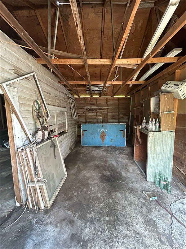 Dilapidated garage interior with weathered wood and concrete floor, blue metal cabinet.