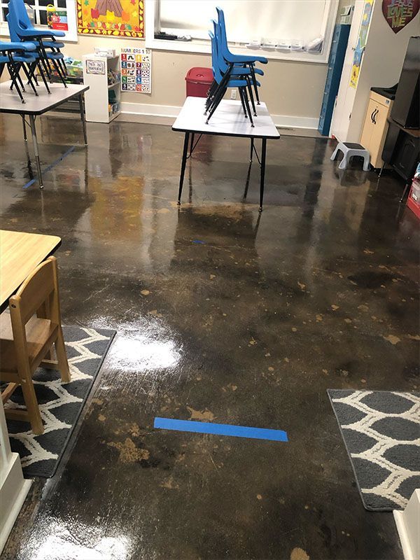 Classroom with tables, chairs, and polished floor. A blue tape line is visible.