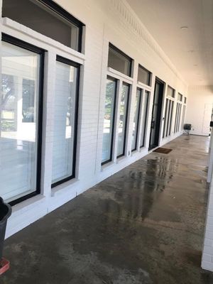 Covered outdoor corridor with white-framed windows and a wet concrete floor