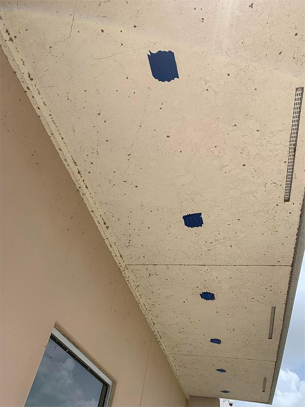 Beige exterior ceiling with blue squares, next to a beige wall with a window.