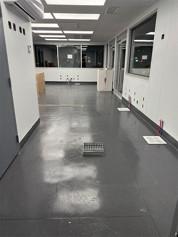 A long office hallway with a black door on the right and a white reception desk on the left.