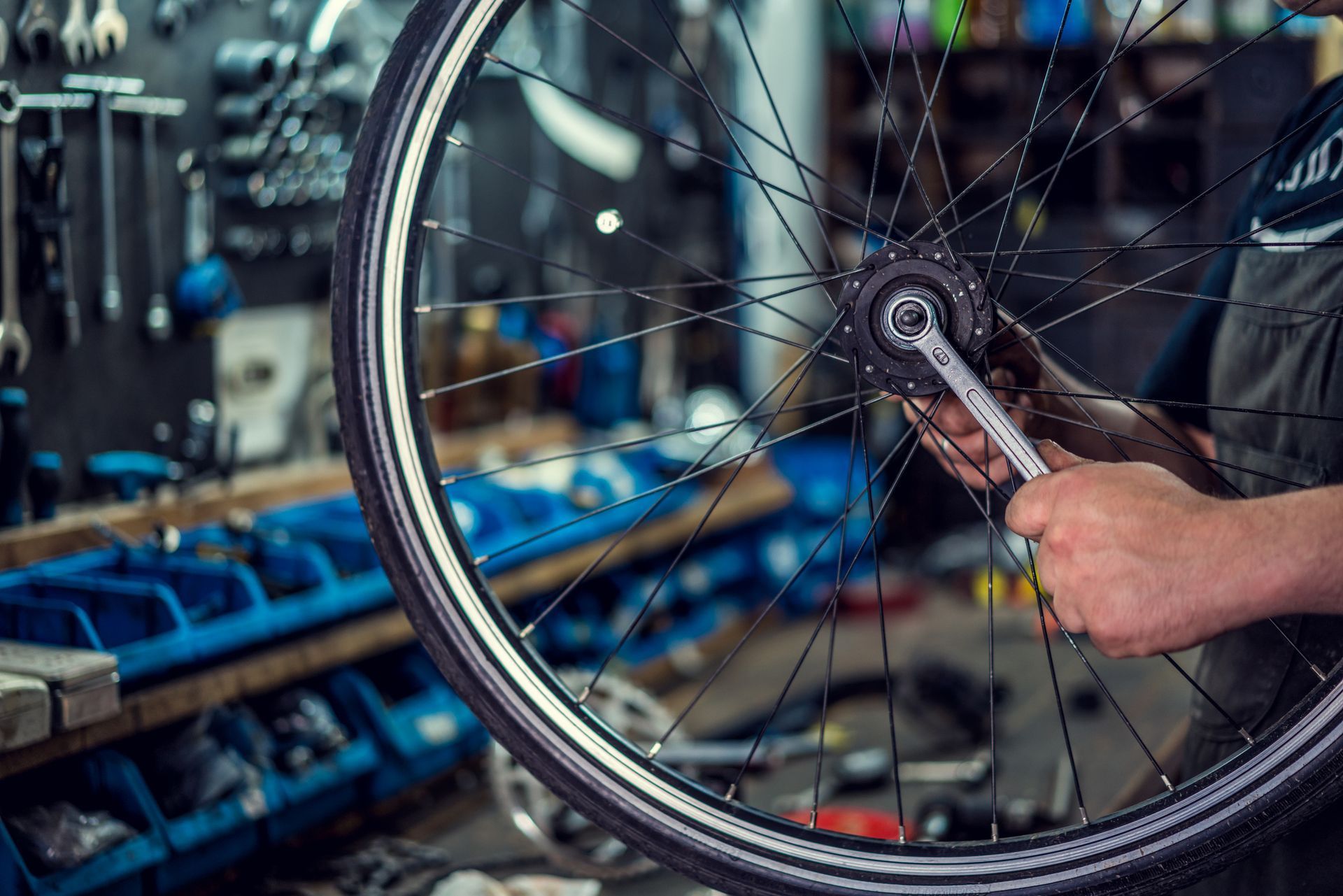 A man is fixing a bicycle wheel with a wrench.