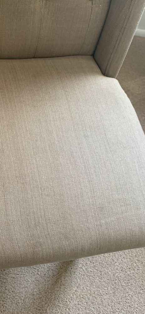 Close-up of a beige upholstered chair cushion and backrest seam.