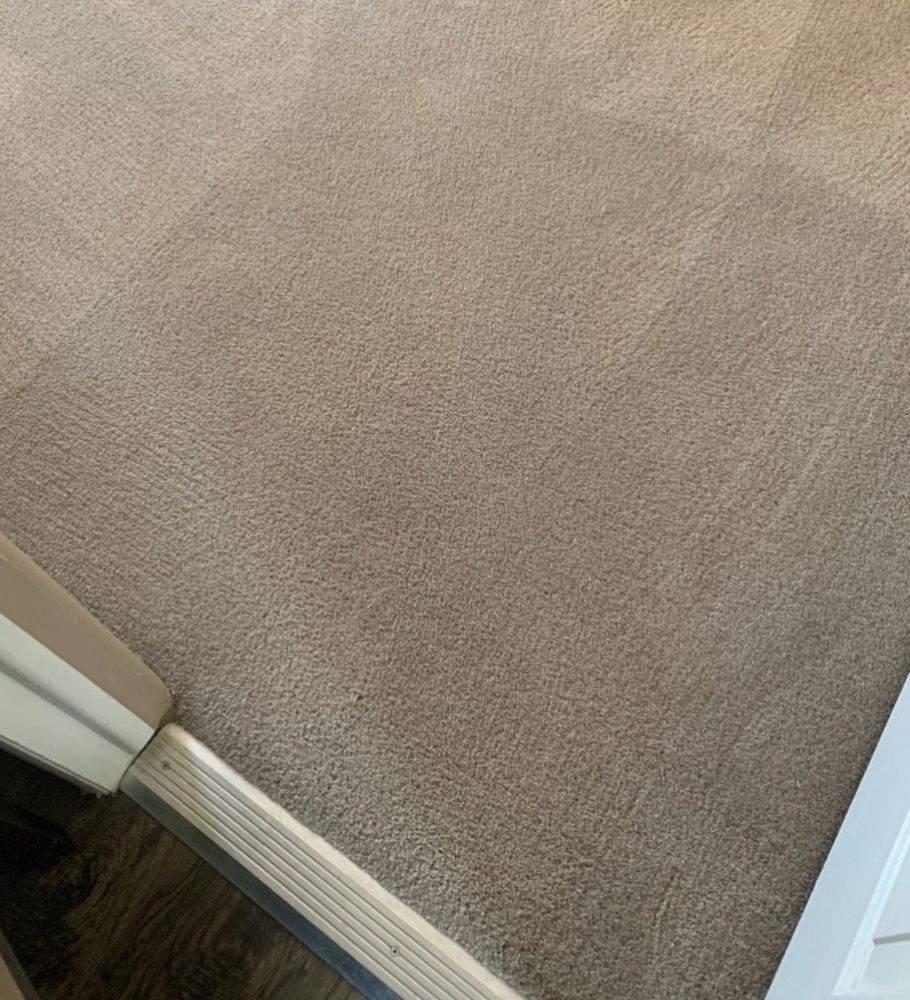 Beige carpeted floor with a white doorway and threshold at the corner of a room