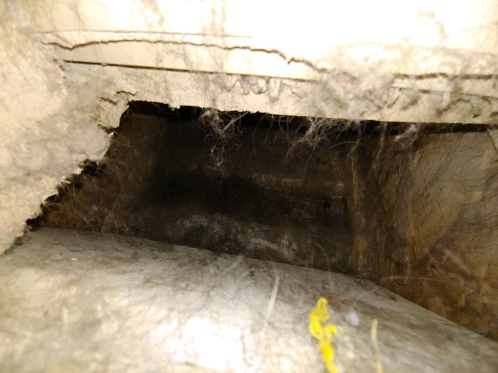Dark opening in a rough stone or concrete wall, resembling a cave or tunnel entrance.